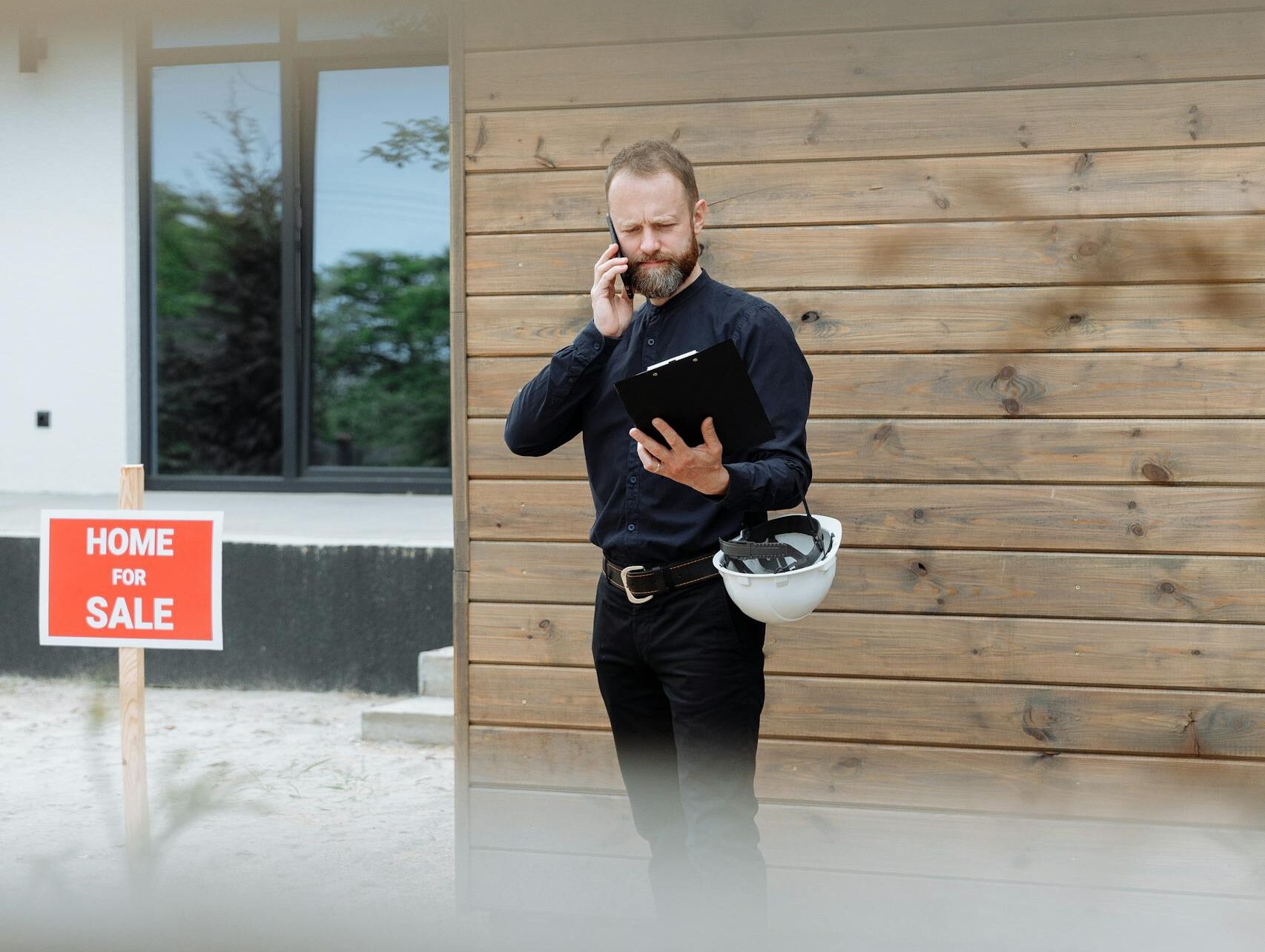 A Man on a Phone Call Reading a Document on a Clipboard