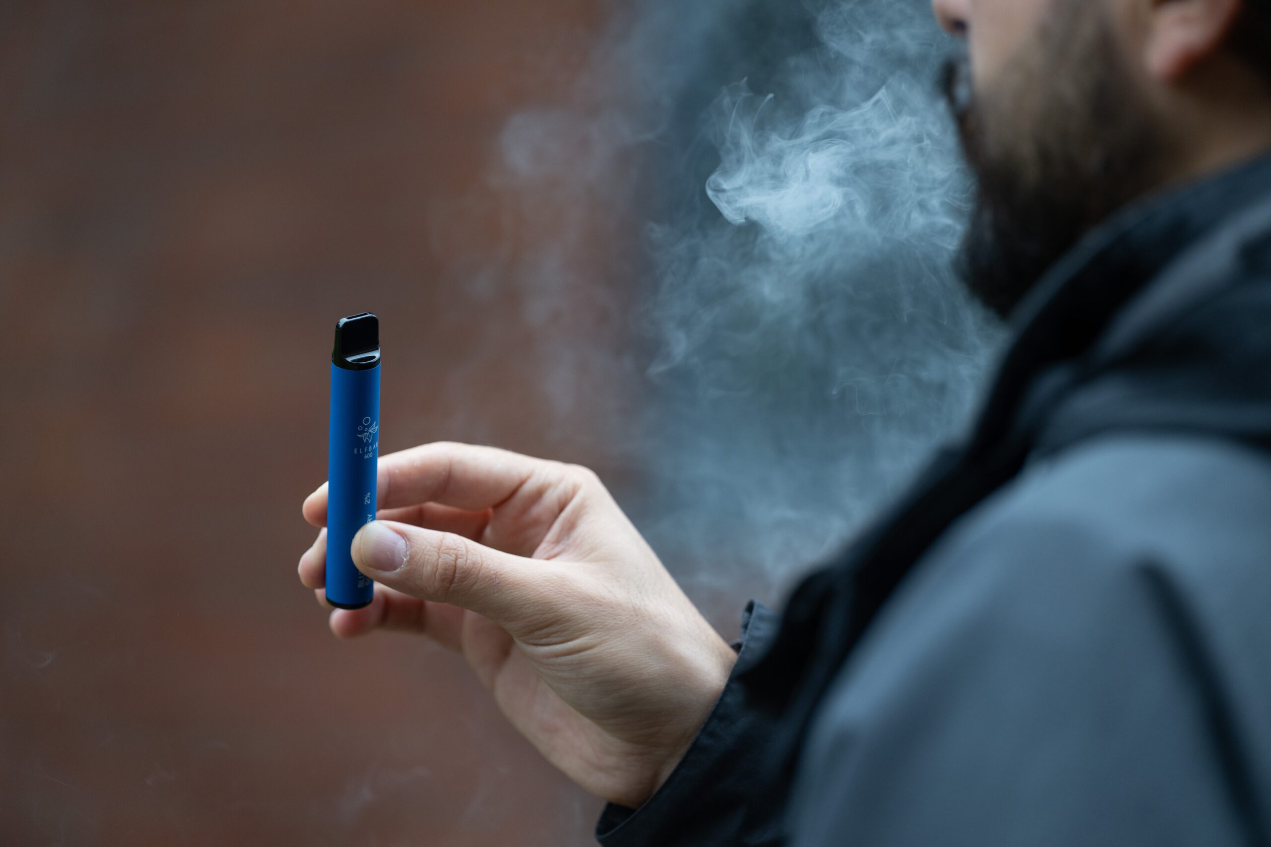 man smoking a vape E-cigarette from behind